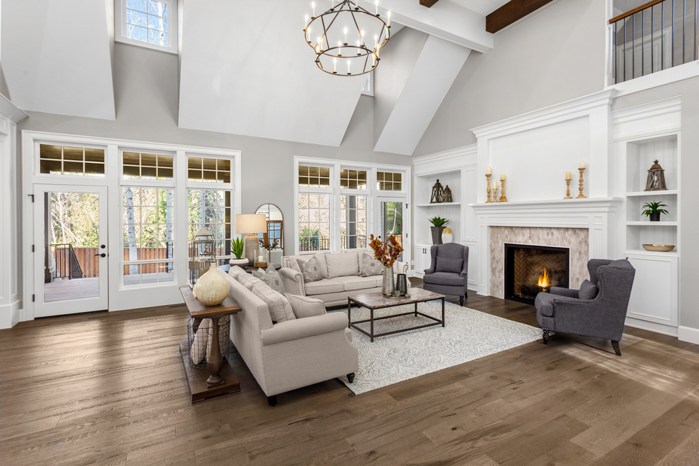 Beautiful living room in new traditional style luxury home. Features vaulted ceilings, fireplace with roaring fire, and elegant furnishings.